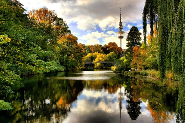 The vibrant colors of autumn set off the inviting lake in Hamburg's Planten un Blomen city park. Just beyond, the Heinrich Herz communications tower.